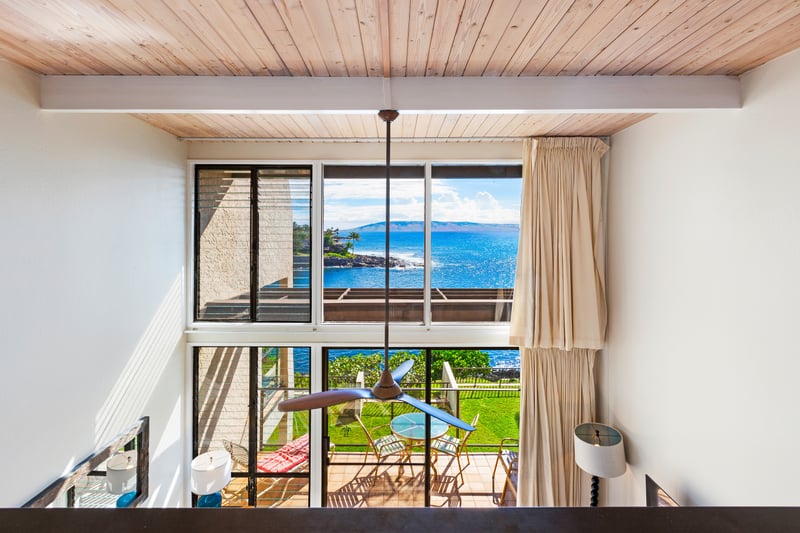 Sunlight pours through two-story glass, dancing across coastal décor and views that stretch far beyond the lanai NAP-C18