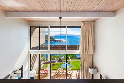 Sunlight pours through two-story glass, dancing across coastal décor and views that stretch far beyond the lanai NAP-C18