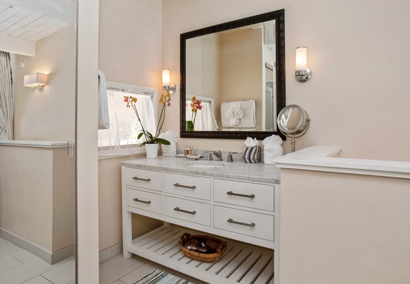 Crisp white cabinetry and sleek hardware are elevated by sculptural orchids and rich accents of black-framed elegance