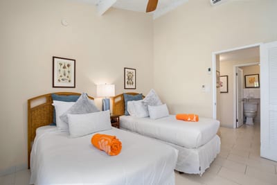 Twin-bed guest room with vaulted ceilings, bright windows, tropical accents, and warm wood furniture for pure comfort