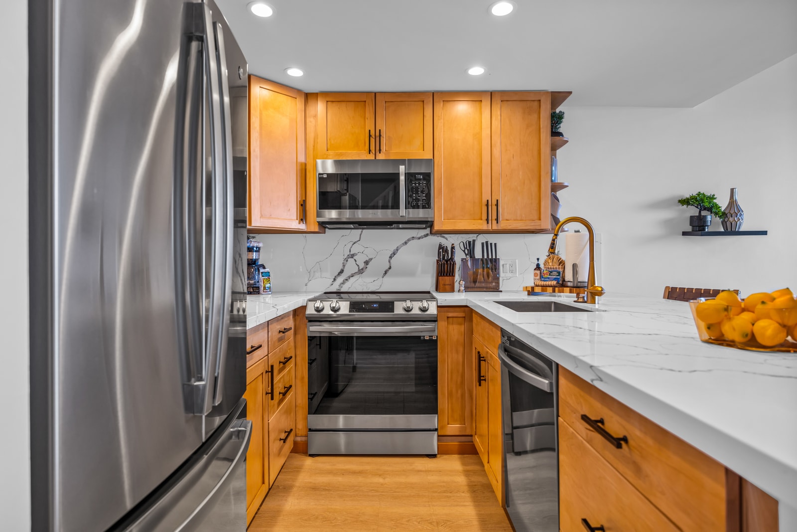 Stainless refrigerator and warm wood finishes bring a polished look, with everything close at hand for easy island cooking. NAP-C32