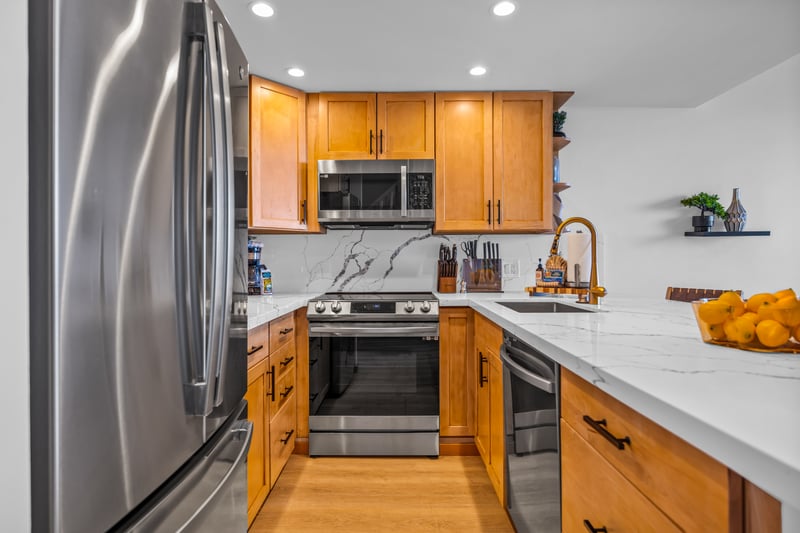 Stainless refrigerator and warm wood finishes bring a polished look, with everything close at hand for easy island cooking.
