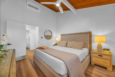 Another primary bedroom angle shows bright white walls and warm wood accents, creating a simple retreat after ocean days.