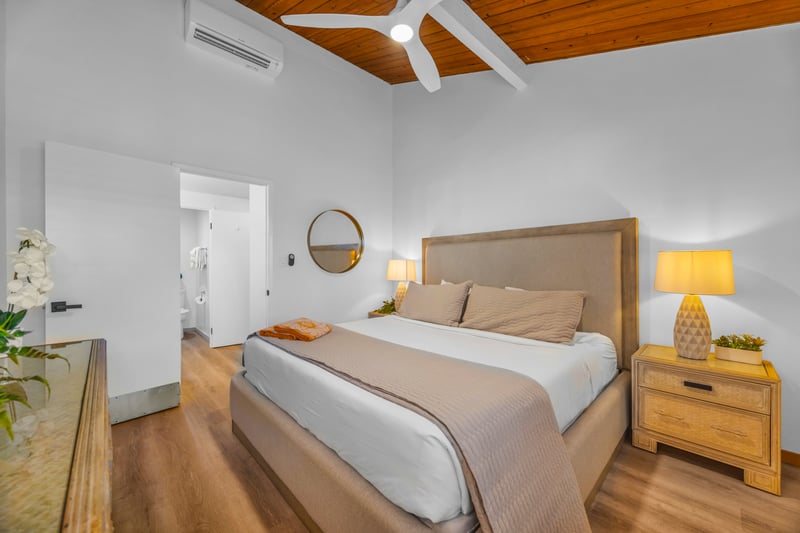 Another primary bedroom angle shows bright white walls and warm wood accents, creating a simple retreat after ocean days.