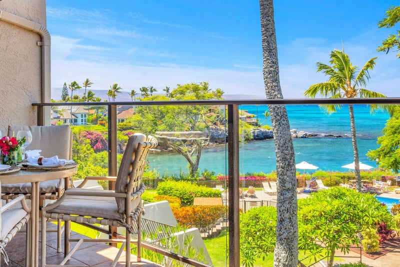 Oceanfront lanai with outdoor dining and panoramic views of turquoise waters, lush gardens, and the pool below — perfect for a tropical escape. NAP-C37