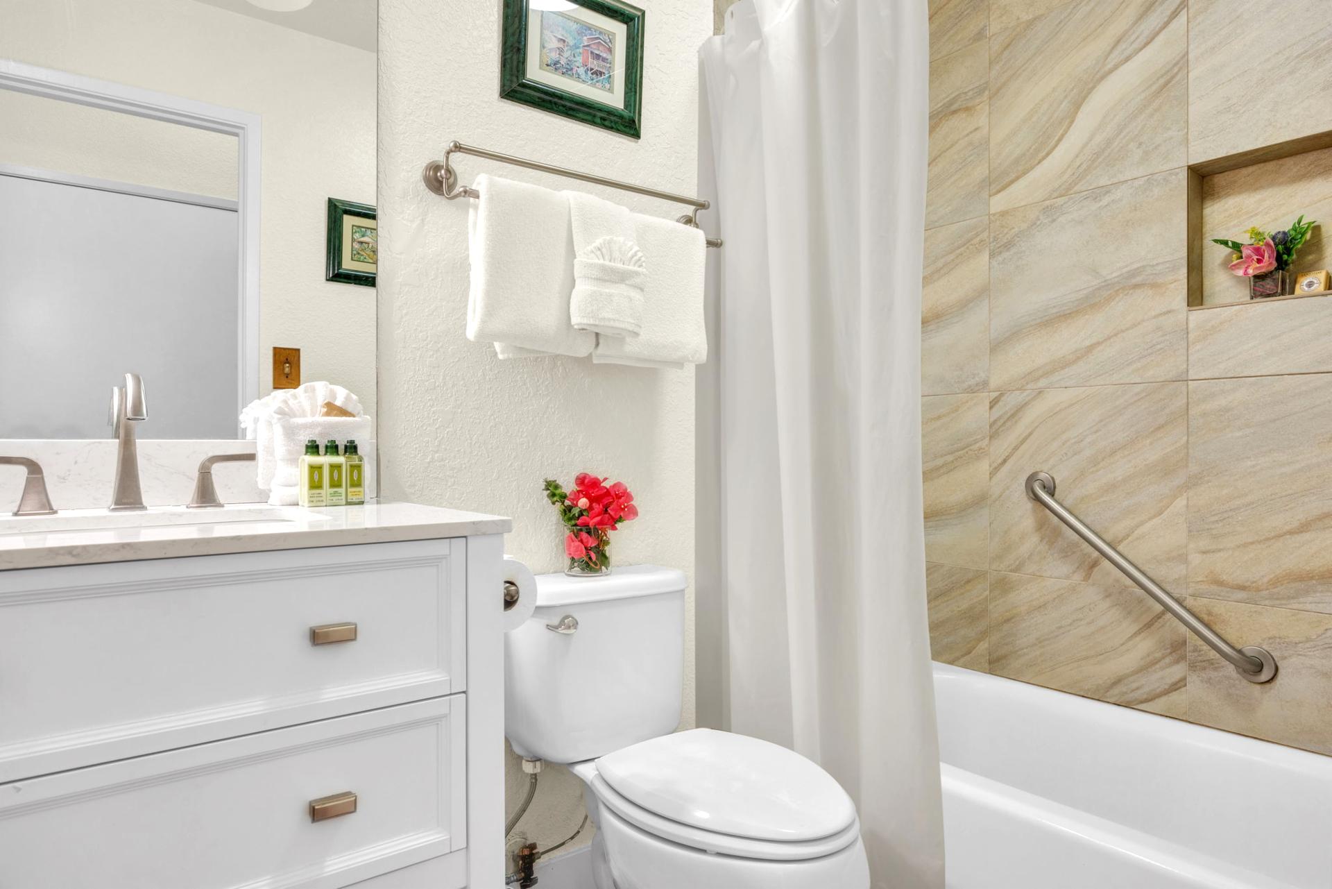 Bright guest bathroom with quartz vanity, tiled shower/tub combo, and thoughtful island touches.