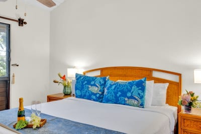 Bright, inviting bedroom with tropical accents and cozy linens for a restful night’s sleep. NAP-C37