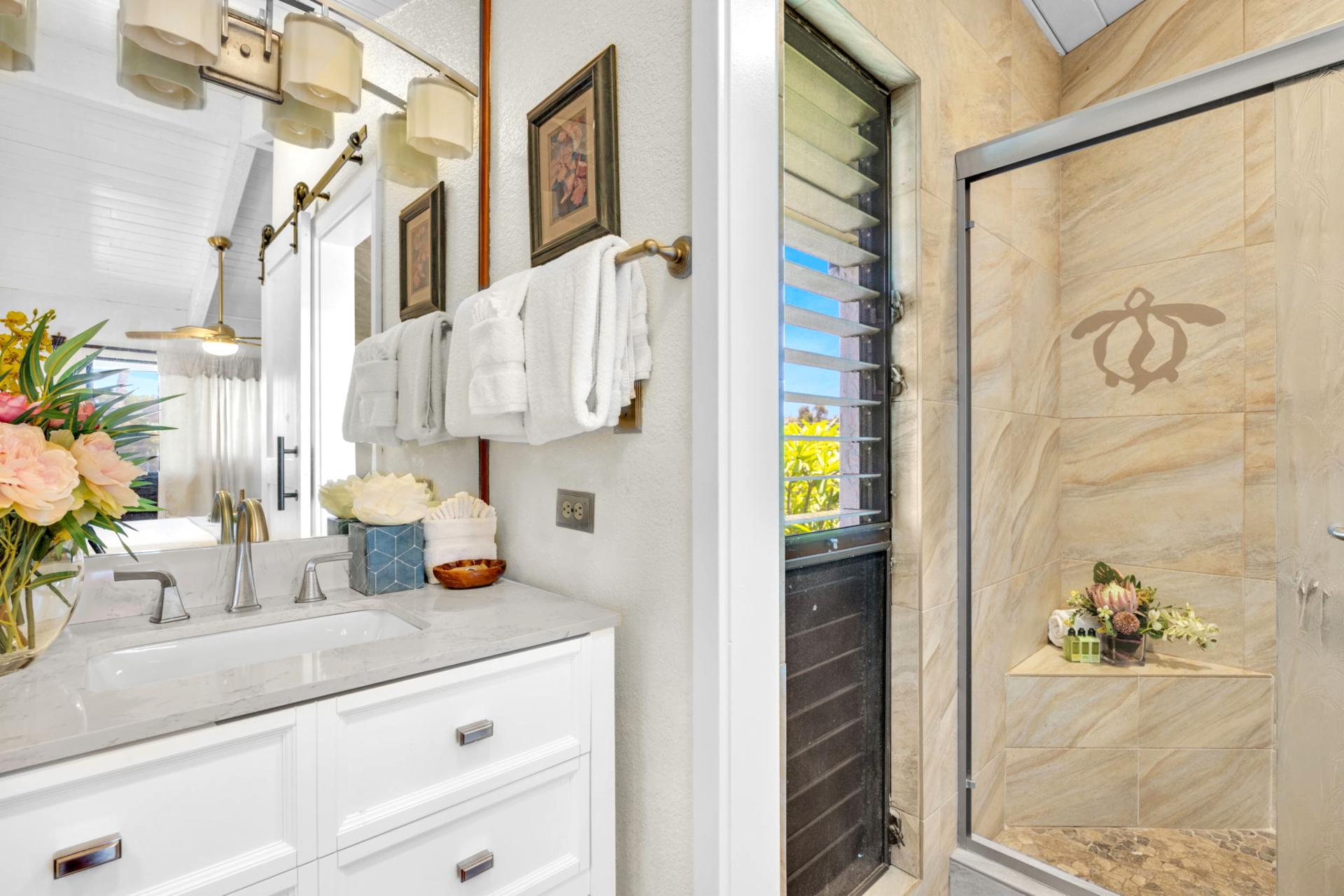 Elegant bathroom with quartz countertop, fresh floral touches, and a spa-style shower featuring a charming sea turtle design NAP-C37