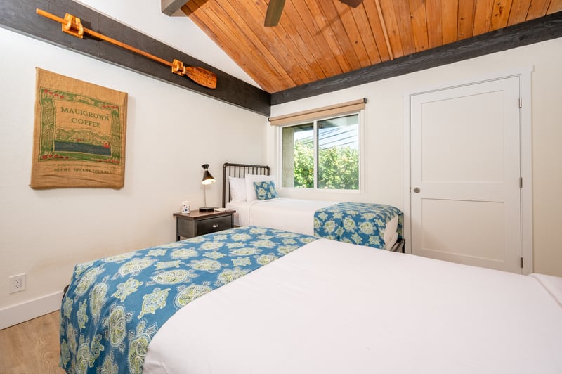 This airy twin room features wood-beam ceilings, island decor, large windows, and soft natural lighting NAP-C43