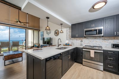 Cook in comfort with sleek black cabinets, exposed brick, modern lighting, and a bright open layout by the lanai