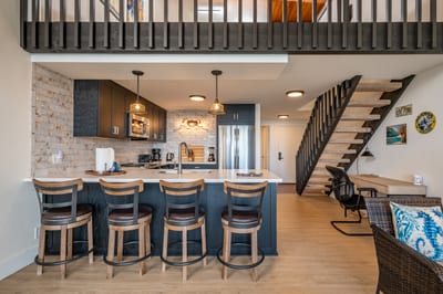 This modern kitchen features sleek dark cabinetry, pendant lighting, and a brick backsplash that adds rustic charm