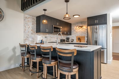 Gather around the spacious island with rich wood stools, textured stone walls, and warm loft-style ambiance