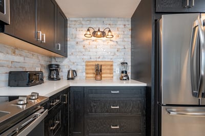 Open to ocean breezes, this elegant kitchen pairs bold cabinetry with rustic textures and a clean, polished vibe