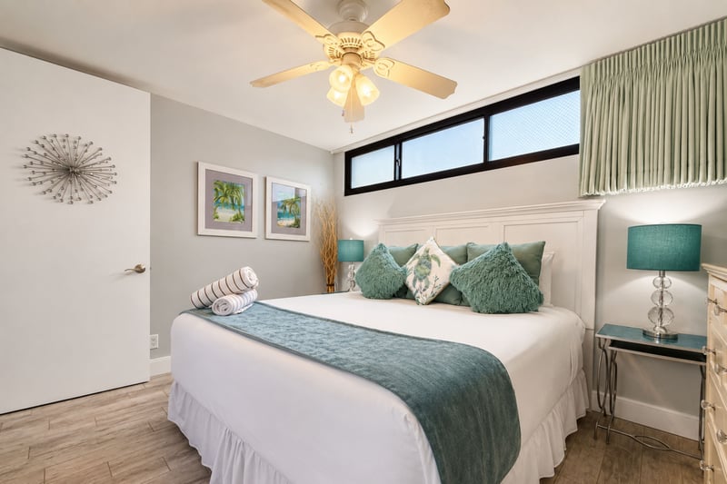 King bedroom with crisp linens, full dresser, and ceiling fan for cool, restful nights.