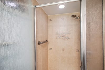 Walk-in shower with frosted glass door and natural stone floor for a clean, modern refresh.