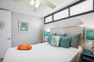King bedroom with crisp linens, full dresser, and ceiling fan for cool, restful nights.