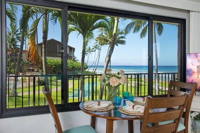 Indoor dining for four with tropical garden views and ocean glimpses through the windows.