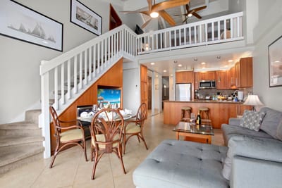 Sailboat prints, a spiral of white stairs, and rattan dining touches make this airy hideaway a charming tropical delight