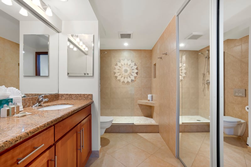 This guest bath offers a granite vanity, walk-in shower with glass doors, and warm tilework for a polished, calming feel