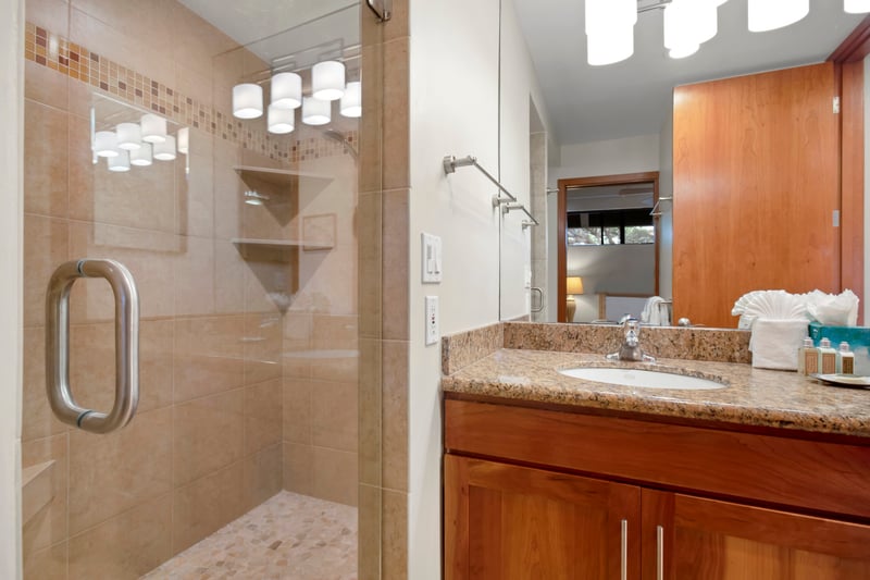 A glass-enclosed shower, granite countertops, and thoughtful touches make this guest bathroom both refined and restful