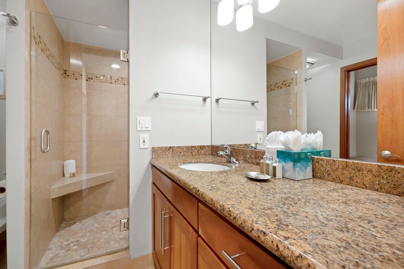With sleek wood cabinetry, soft lighting, and a stone-tiled shower, this guest bath welcomes with style and comfort