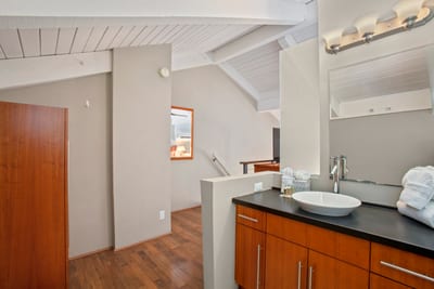 This guest bath blends modern elegance with warmth—featuring a vessel sink, rich wood cabinetry, and soft lighting