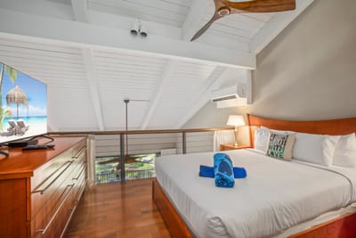 A lofted guest retreat where white beams soar, warm woods glow, and the bed invites breezy island rest