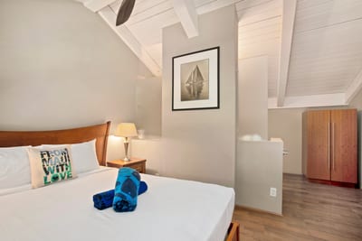 This guest room blends sloped ceilings, tropical light, and crisp bedding into a haven of peaceful charm