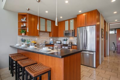 This designer kitchen offers polished countertops, a breakfast bar, and custom cabinets in a rich cherry wood tone