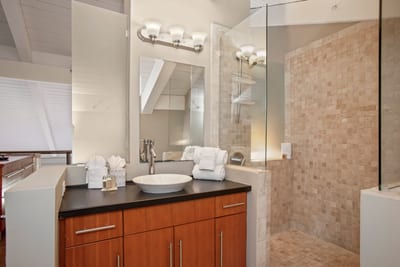 With rich wood textures and a stone-tiled shower, this airy master bath blends sleek design with spa-like tranquility