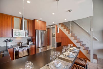Enjoy a fully equipped gourmet kitchen with built-in wine storage, floating shelves, and gleaming steel accents