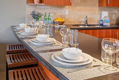 Gather around a spacious island with bar seating, stone countertops, elegant place settings, and warm wood finishes