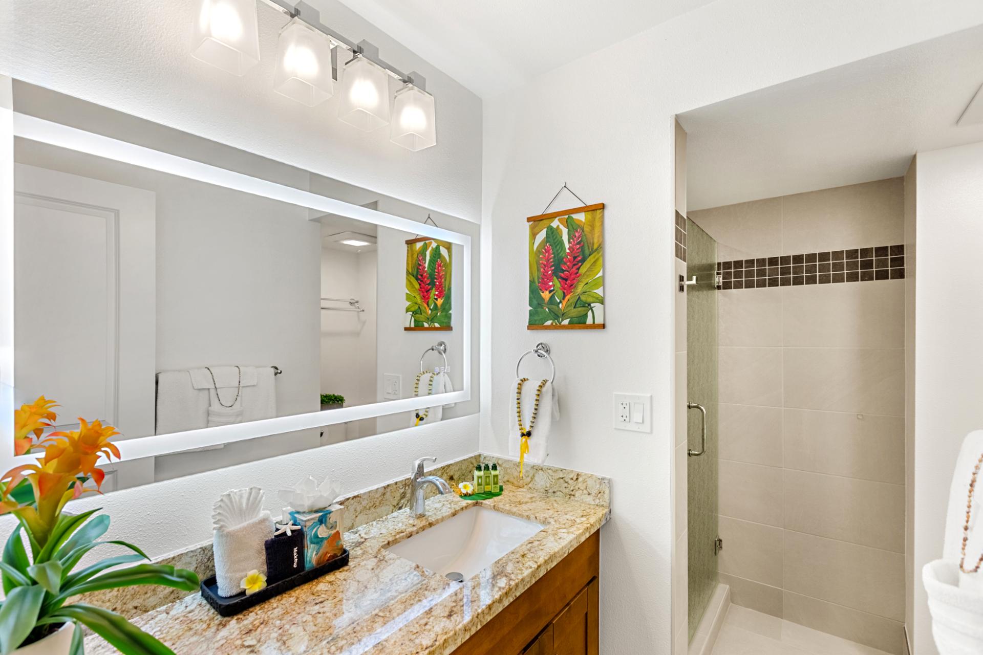 Granite vanity and full mirror offer plenty of space to get ready, with bright lighting and convenient storage below.
