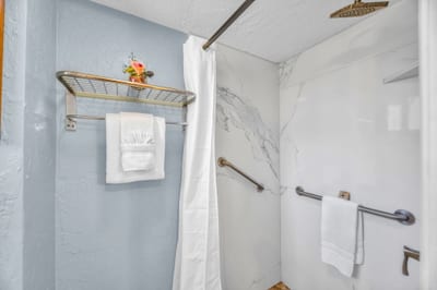 Floor-to-ceiling marble-look tile and a rainfall head finish the walk-in shower
