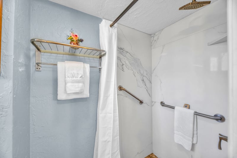 Floor-to-ceiling marble-look tile and a rainfall head finish the walk-in shower