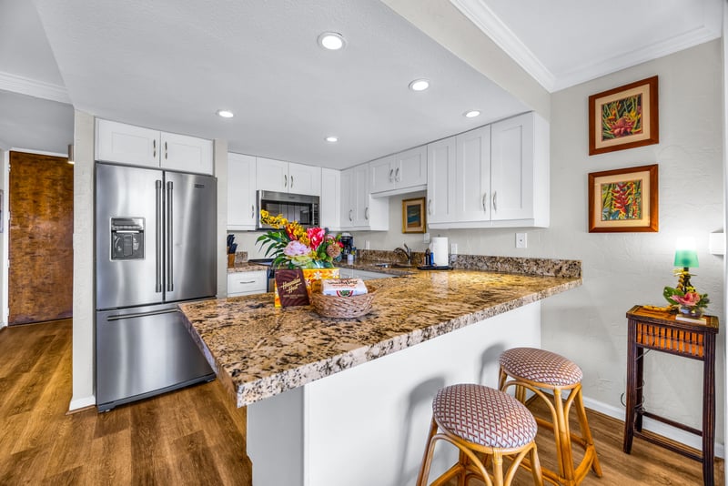The kitchen features a breakfast bar with two stools for convenient seating