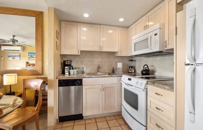 A cozy, fully equipped kitchen awaits with modern appliances, tiled backsplash, and charming under-cabinet lighting