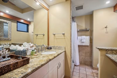 This master bath exudes tropical charm with granite countertops, wood-trimmed mirrors, and handcrafted island touches