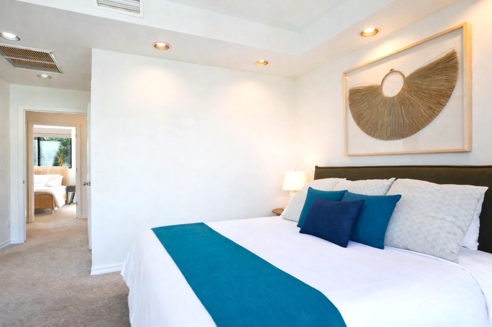 Sink into a cloud of calm—this master bed is framed by glass, greenery, and serene neutral tones   