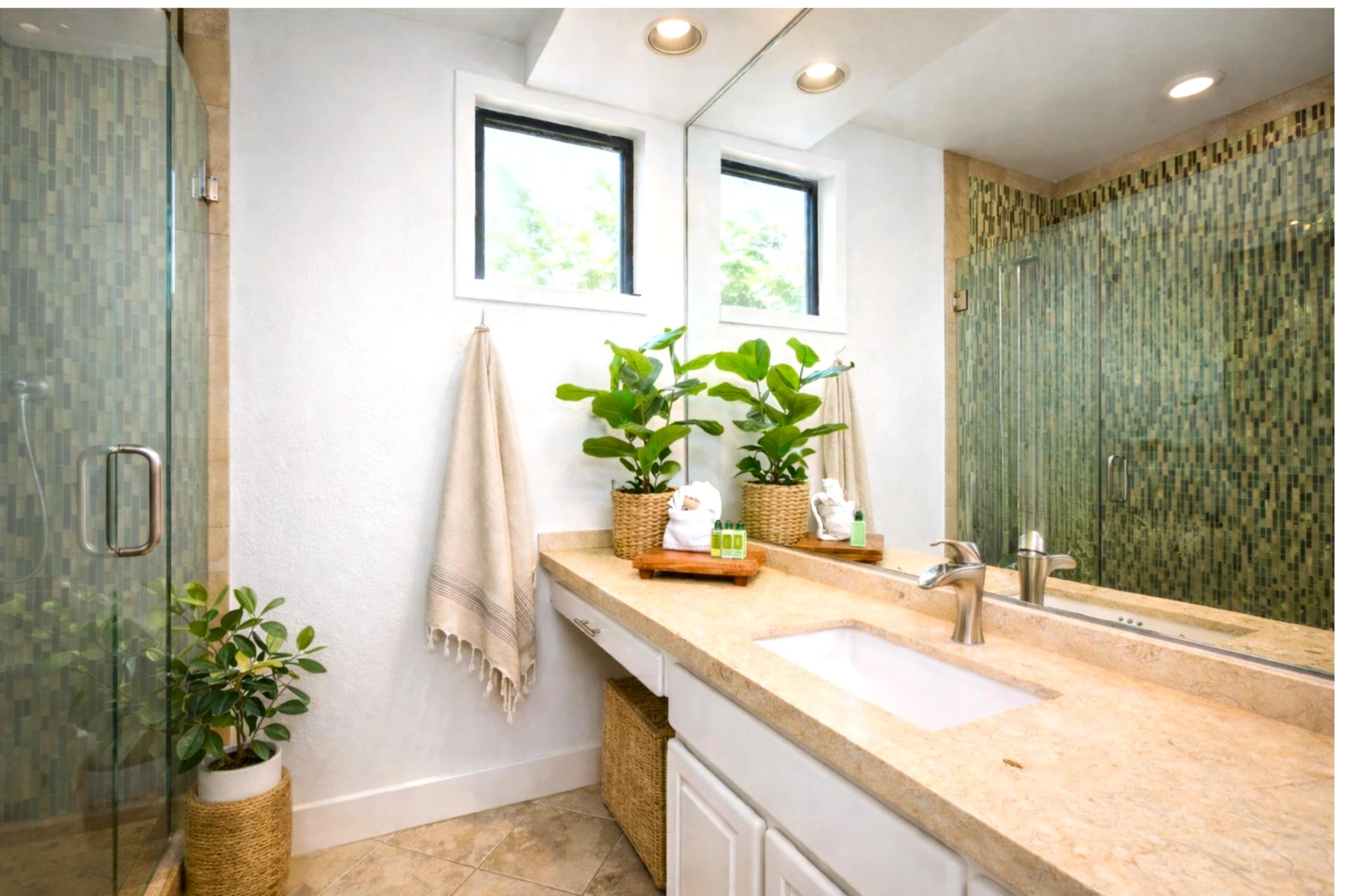  This tranquil master bath features a walk-in glass shower with custom mosaic tile and a serene, spa-like ambiance  