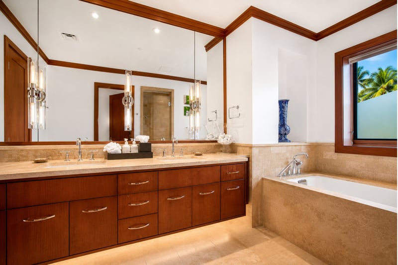 A generous double vanity with rich wood cabinetry and glowing pendant lights invites graceful starts and gentle ends