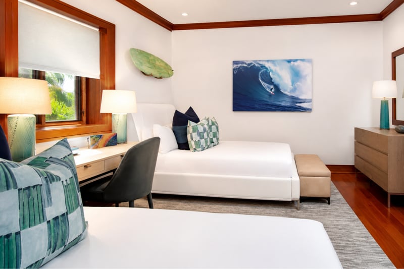 Twin beds with crisp white linens and bold accent pillows offer comfort with a splash of coastal flair