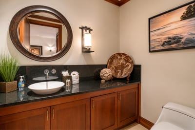 The half bath is well lit and comfortable, featuring a granite countertop and tasteful decor