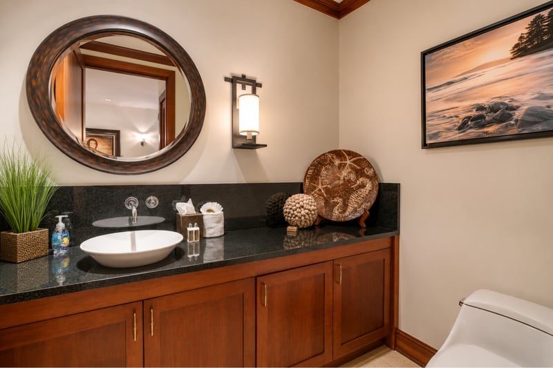 The half bath is well lit and comfortable, featuring a granite countertop and tasteful decor
