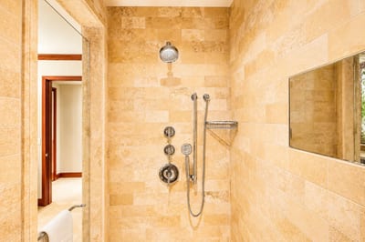Step into a spa-style walk-in shower with natural stone walls and luxe fixtures