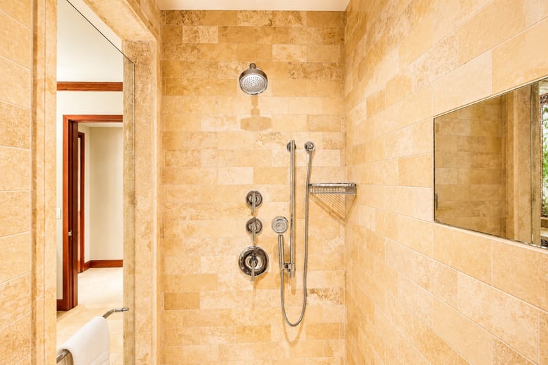 Step into a spa-style walk-in shower with natural stone walls and luxe fixtures