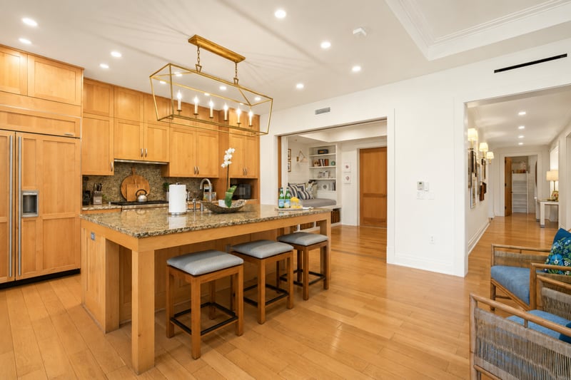 Chef's kitchen at The Resort at Kapalua Bay MON-2206 — granite island seating for three beneath a brass candle-style chandelier MON-2206
