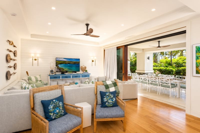 Living room at The Resort at Kapalua Bay MON-2206 — sectional and armchairs facing a wall-mounted TV, with French doors to the dining lanai MON-2206
