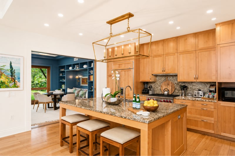 Kitchen island at The Resort at Kapalua Bay MON-2206 — linear brass chandelier and open flow to the den and dining lanai MON-2206