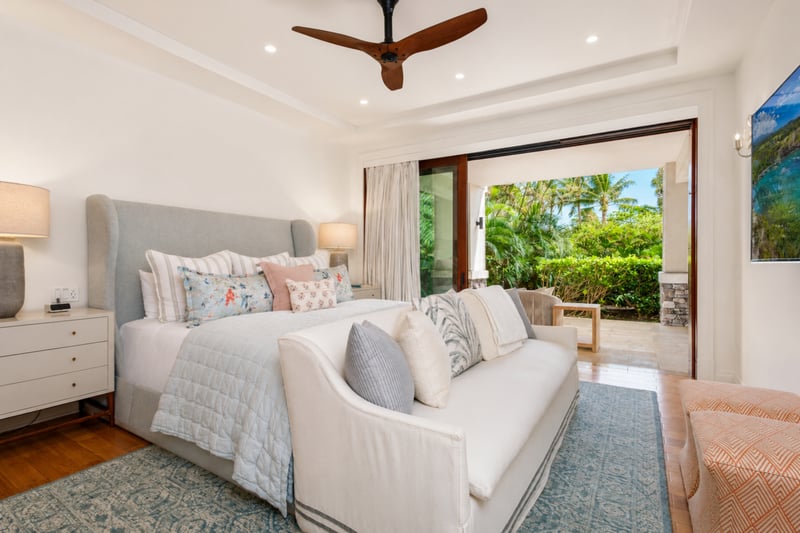 Primary bedroom at The Resort at Kapalua Bay MON-2206 — wood headboard, chaise daybed, and a gallery wall of framed botanical prints MON-2206